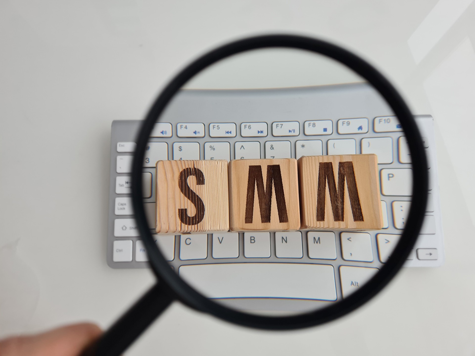 SMM word written on cubes with magnifying glass on computer keyboard and business